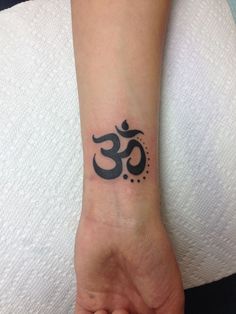 a small wrist tattoo with an omen symbol on it