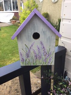 a birdhouse with purple flowers painted on it