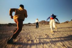 three people are running in the desert on a sunny day