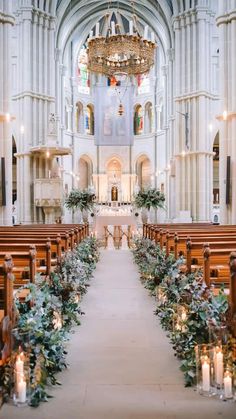 an empty church filled with wooden pews covered in greenery and lit by candles