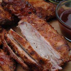 some meat is cut up and sitting on a cutting board with ketchup next to it