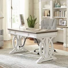 a white desk with a laptop on it in front of a chair and bookshelf