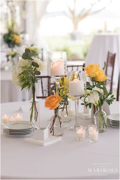 a table topped with vases filled with flowers and candles