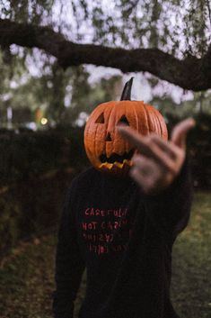 a person in a black shirt with a jack o lantern on their head and hands out