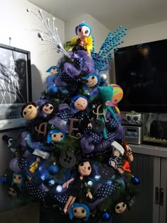 a christmas tree decorated with blue and purple items in the shape of people sitting on top of it