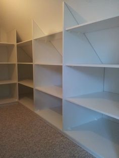 an empty room with white shelving and carpeted flooring in the middle of it