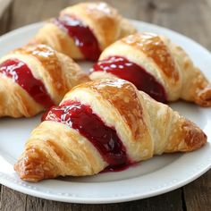 four croissants on a white plate covered in jelly