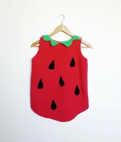 a red shirt with black drops on it and a green bow tie hanging from a wooden hanger