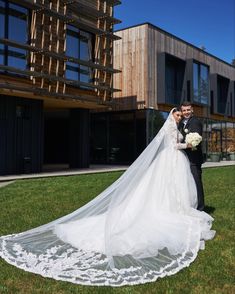 a bride and groom pose for a photo in front of a building with large windows