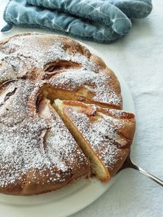 a white plate topped with a cake covered in powdered sugar on top of a table