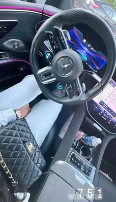 a woman sitting in the driver's seat of a car with her hand on the steering wheel