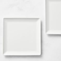 two white square plates sitting on top of a table