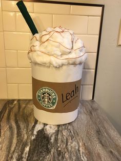 a starbucks drink with whipped cream and a green straw in it's cup sitting on a counter