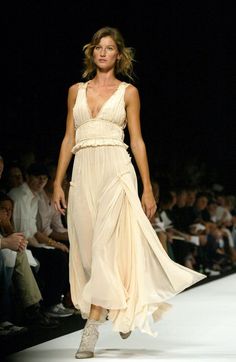 a woman is walking down the runway in a dress