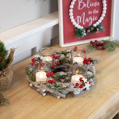 some candles are sitting on a table with christmas decorations and greenery around it,