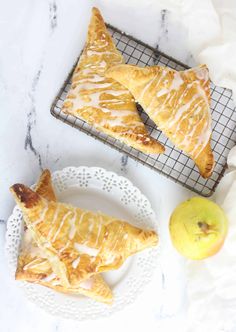 two pastries sitting on top of a white plate next to an apple