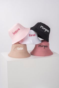 three hats with names on them sitting on top of a white block