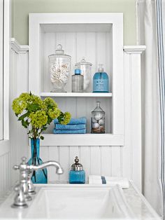 a white sink sitting under a bathroom mirror next to a shower stall with shelves above it