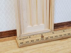 a ruler is on the floor next to a wooden door with a white paneling