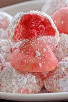 some powdered sugar covered pastries on a white plate with pink and red toppings