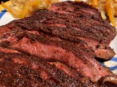 two pieces of steak on a blue and white plate with onion wedges next to it