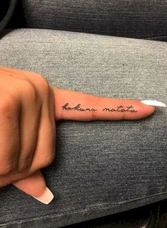 a person's hand with a small tattoo on the middle finger that reads, human nature