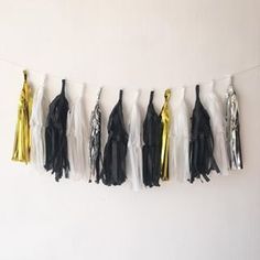 black, white and gold tassels hanging from a string on a wall in front of a white wall