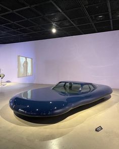 a large blue car sitting on top of a white floor next to a purple wall