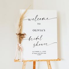 a welcome sign on an easel for a bridal shower with dried flowers in it