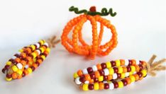 three beaded pumpkins and corn on the cob are sitting next to each other