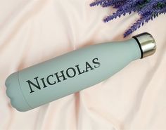 a bottle with the name nicholas on it next to lavender flowers