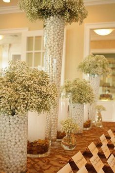 there are many tall vases with flowers in them on the table at this wedding reception