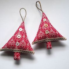 two red and white ornaments are hanging from strings on the wall, one is decorated with buttons