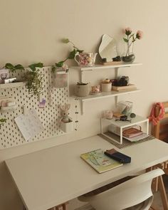 a white desk topped with lots of shelves filled with books and plants on top of it