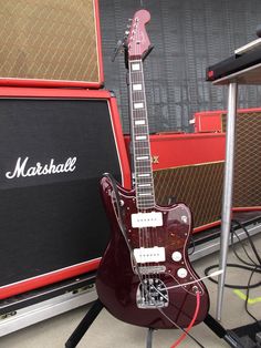 a red guitar sitting on top of a table next to a amp and speaker system