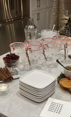 the table is set for christmas dinner with plates, glasses and candy canes on it