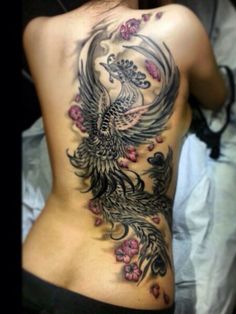 the back of a woman's tattoo with flowers and a bird on her stomach