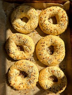 six bagels with poppy seed sprinkles on a baking sheet, ready to be baked