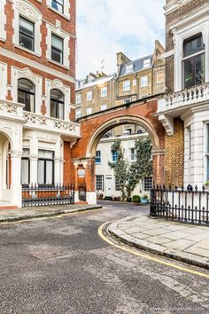 an arch in the middle of a street between two buildings with wrought iron fences on both sides