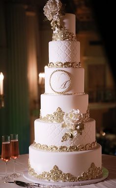 a three tiered wedding cake sitting on top of a table next to wine glasses