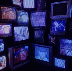 many televisions are stacked up in a dark room