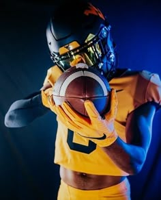 a football player is holding a ball in his right hand and posing for the camera