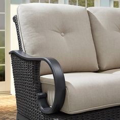 a wicker couch sitting on top of a wooden floor next to a sliding glass door