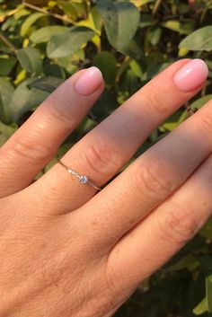 a woman's hand with pink manicured nails and a ring on her finger