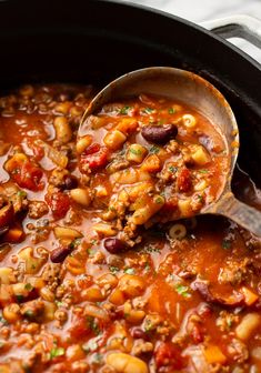 a ladle full of chili and beans in a slow cooker