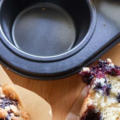 two blueberry muffins sitting on top of a table next to a pan