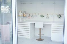 a white desk sitting inside of a room next to a window with flowers on it