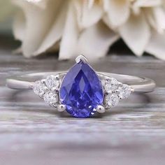 a tan and white diamond ring with a blue stone surrounded by three diamonds on a wooden surface