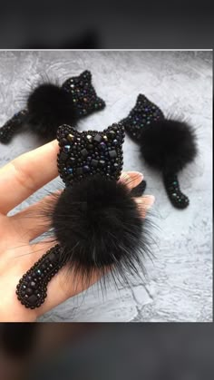 a hand holding a black furry ball and some beads