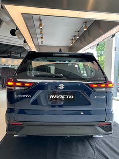 the rear end of a blue suv parked in a showroom